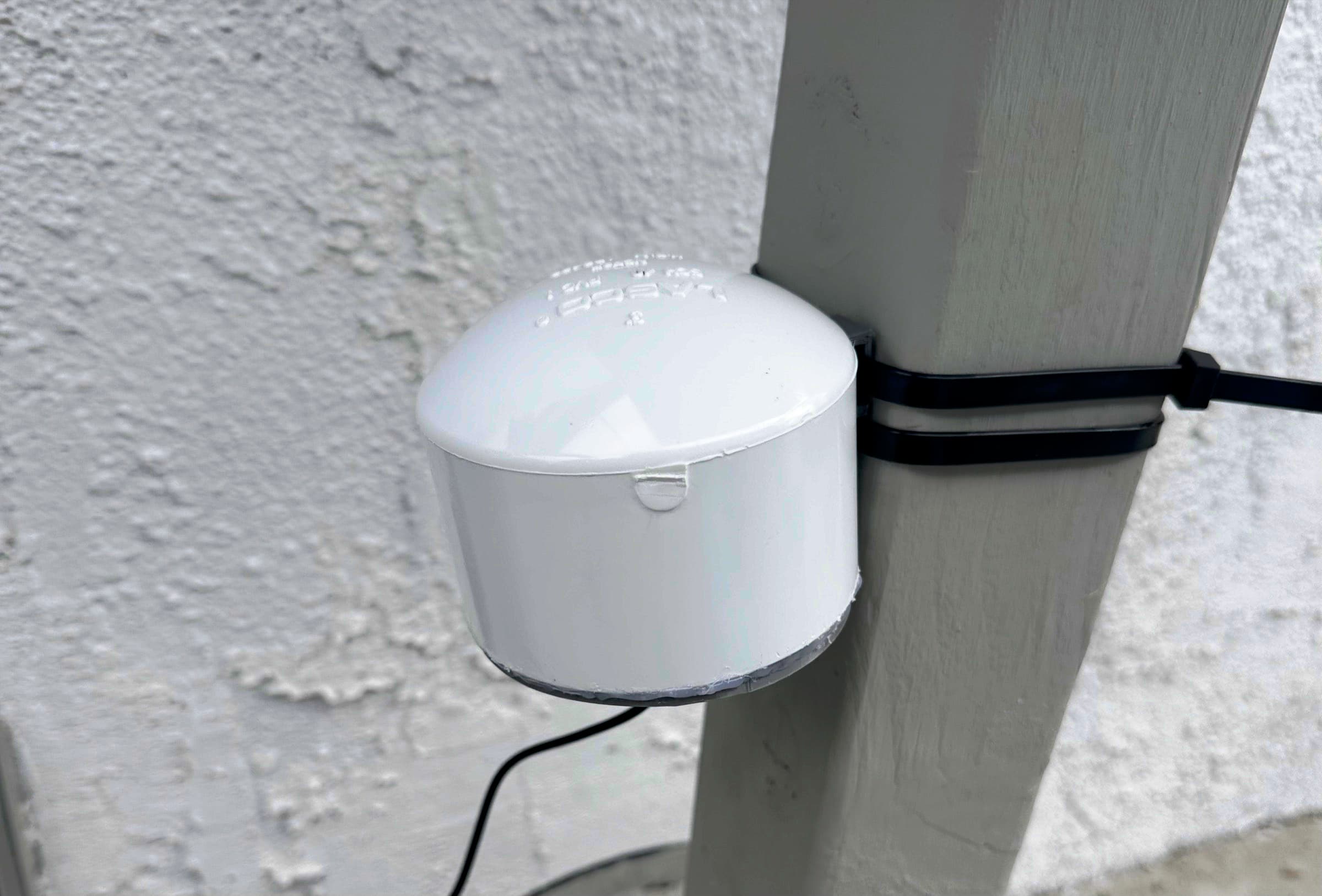 Sensor enclosure zip-tied to an outdoor post